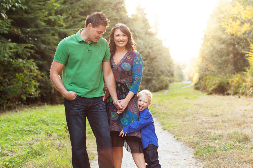 A smiling family walking together on a sunlit woodland path